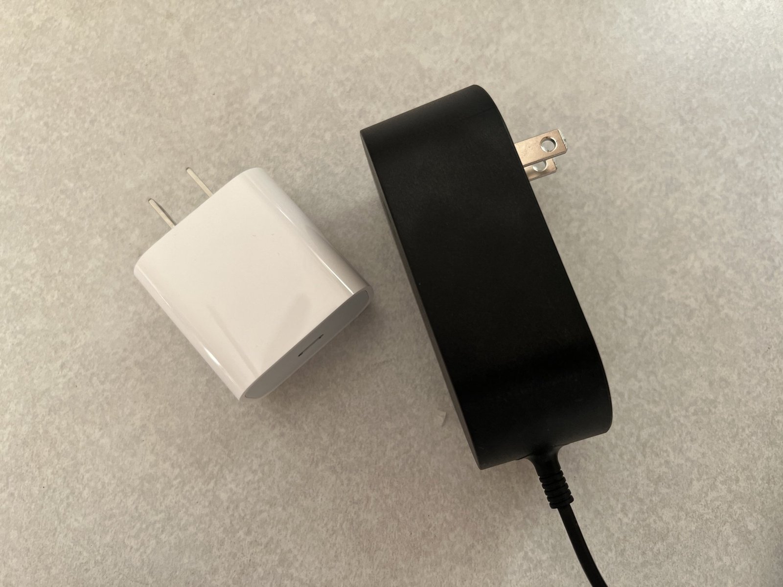 White 20 watt USB-C adaptor from Apple on the left, black attached 15 watt adaptor from Belkin on the right. 