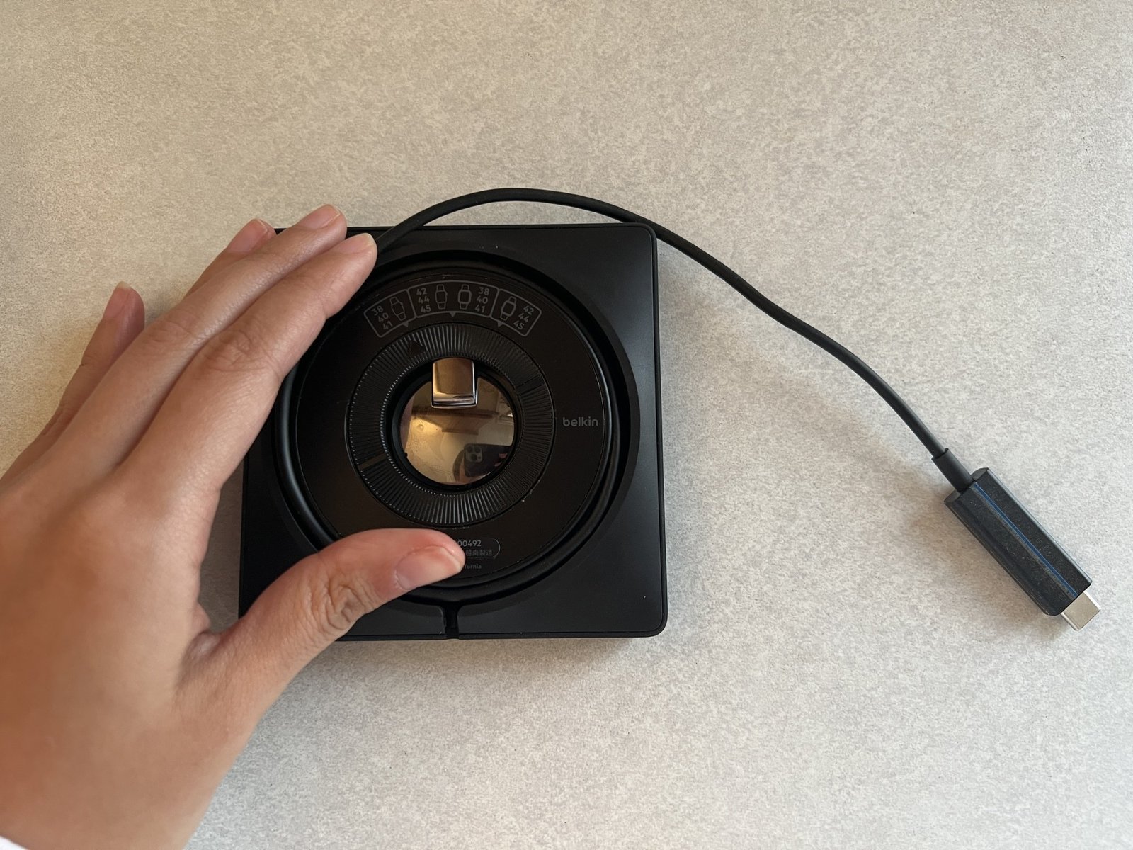 The back of the Belkin charger for Apple Watch, black and showing the winded up cord in a circle module.